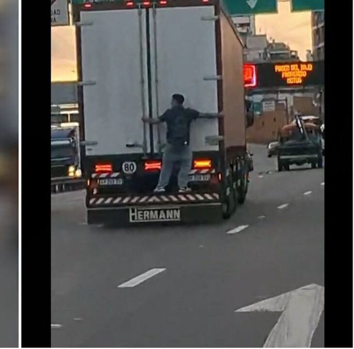 布宜诺斯艾利斯高速公路上青年男子悬挂卡车后部